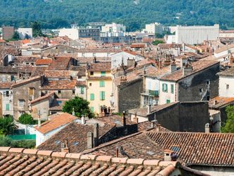Toits de maisons avec des façades colorées et un paysage urbain en arrière-plan.