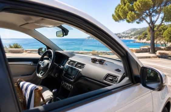 Intérieur d'une voiture avec vue sur la mer et des arbres en arrière-plan.