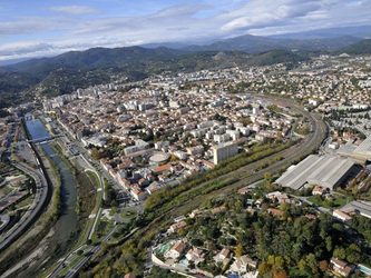 Vue aérienne d'une ville avec des montagnes, une rivière et des bâtiments.